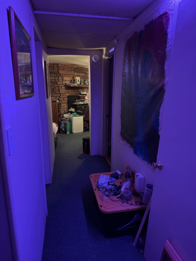 a softly lit hallway opening into a well-lit room with pictures and objects visible