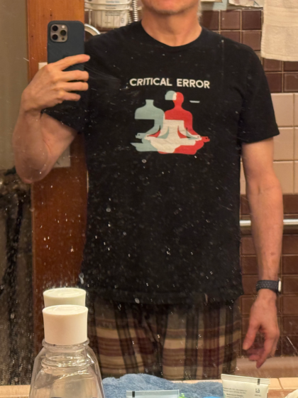 a guy in a dirty mirror wearing a t-shirt of a disjointed yoga pose with the caption "critical error"