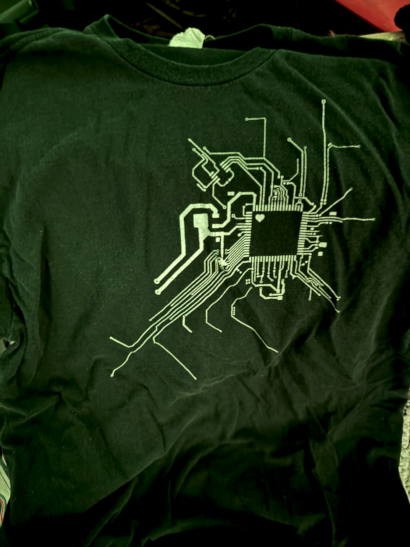 A black t-shirt with a circuit pattern over the heart, with a tiny heart in a chip