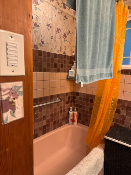 a bathtub surrounded by tile and wallpaper in dated fashion