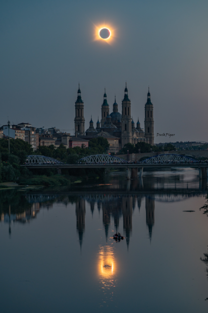 A solar eclipse and its reflection in water with a Spanish cathedral in between